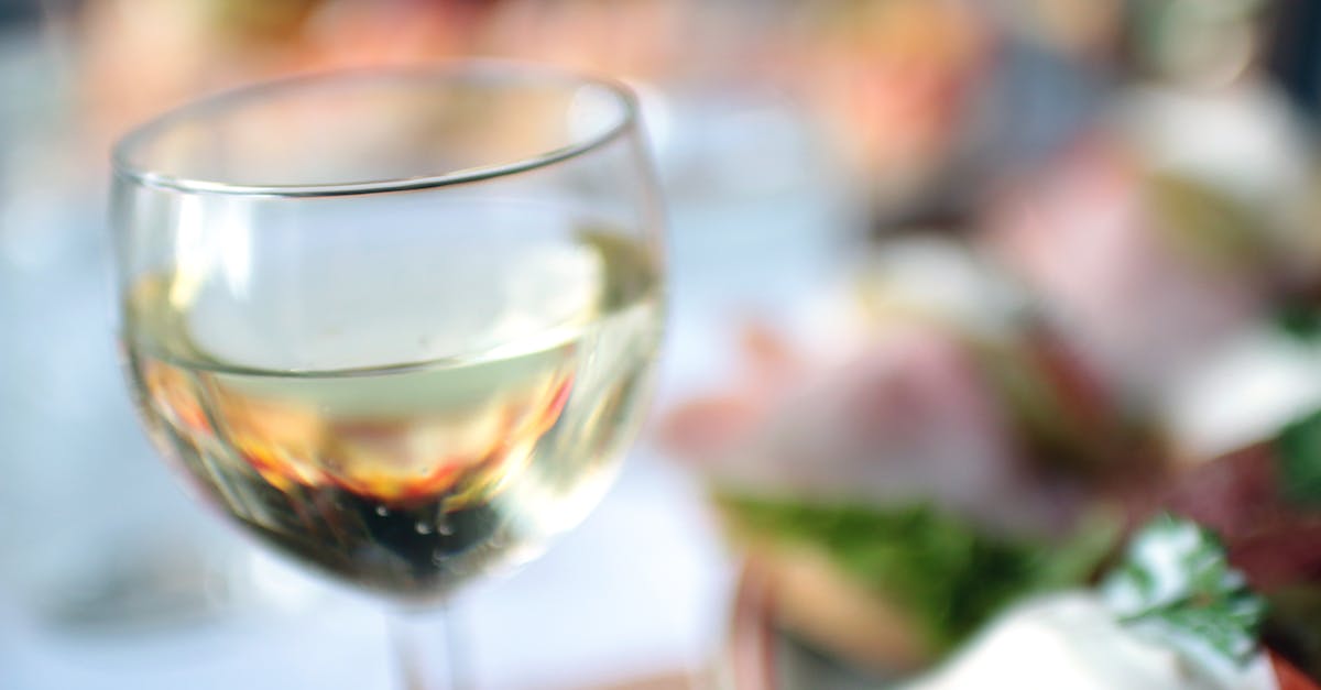 A close-up of a white wine glass in a blurred lunch ambiance.