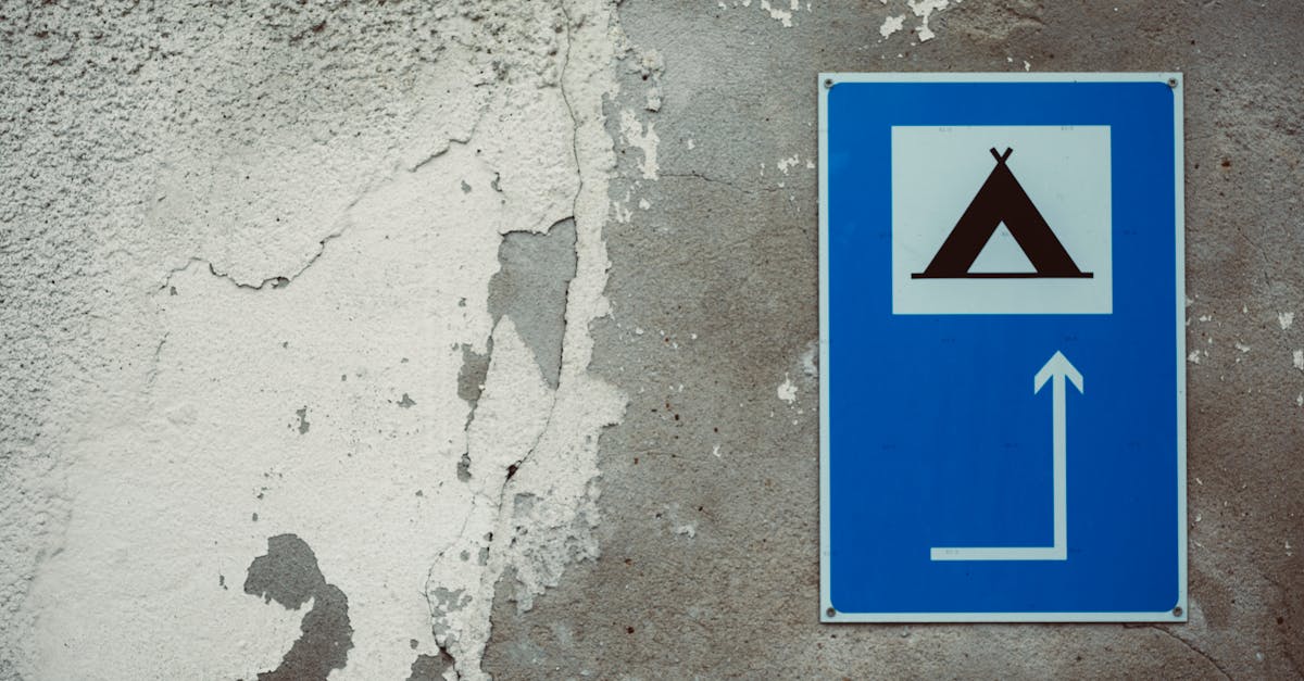 Blue camping direction sign on a vintage, peeling wall surface.