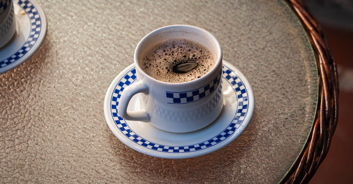 Delightful black coffee served in a blue pattern cup on a glass table outdoors.