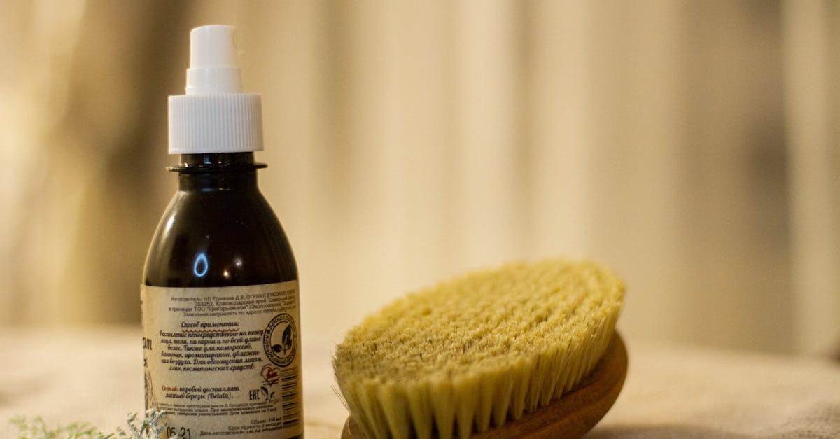 A close-up of a natural bath setup featuring a wooden brush and essential oil bottle.