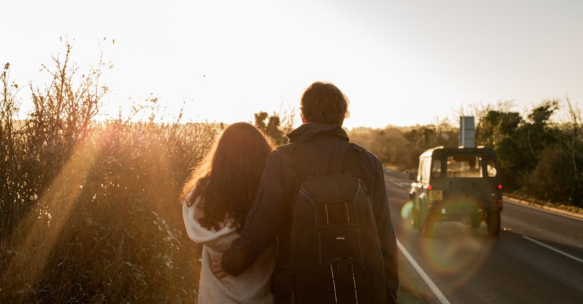 A couple walking together on a countryside road during a warm sunset.