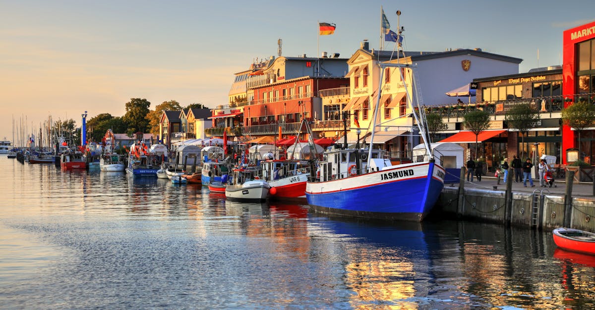 Colorful boats docked at Rostock harbor with sunset reflecting on the calm sea.