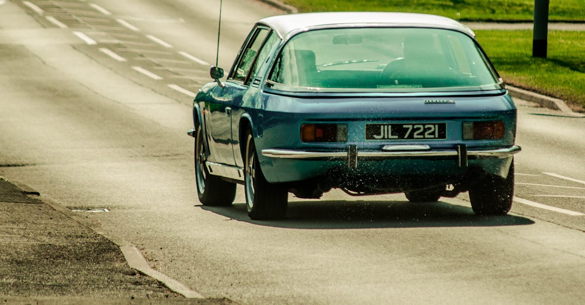 Classic vintage blue sedan with license plate JIL 7221 on an open road during the day.