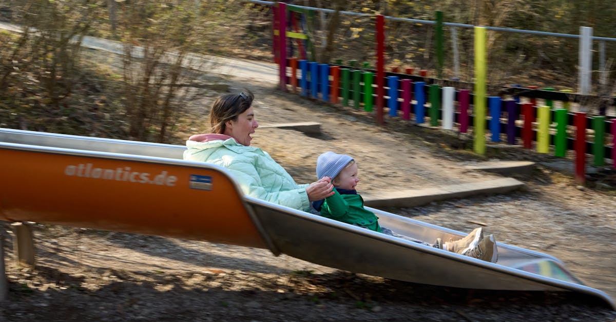 A joyful moment of a mother and child sliding together at a colorful playground in Zürich, Switzerland.