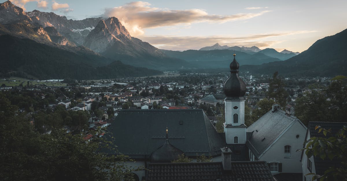 Breathtaking view of Garmisch-Partenkirchen with a church in the foreground and Alps at sunset.