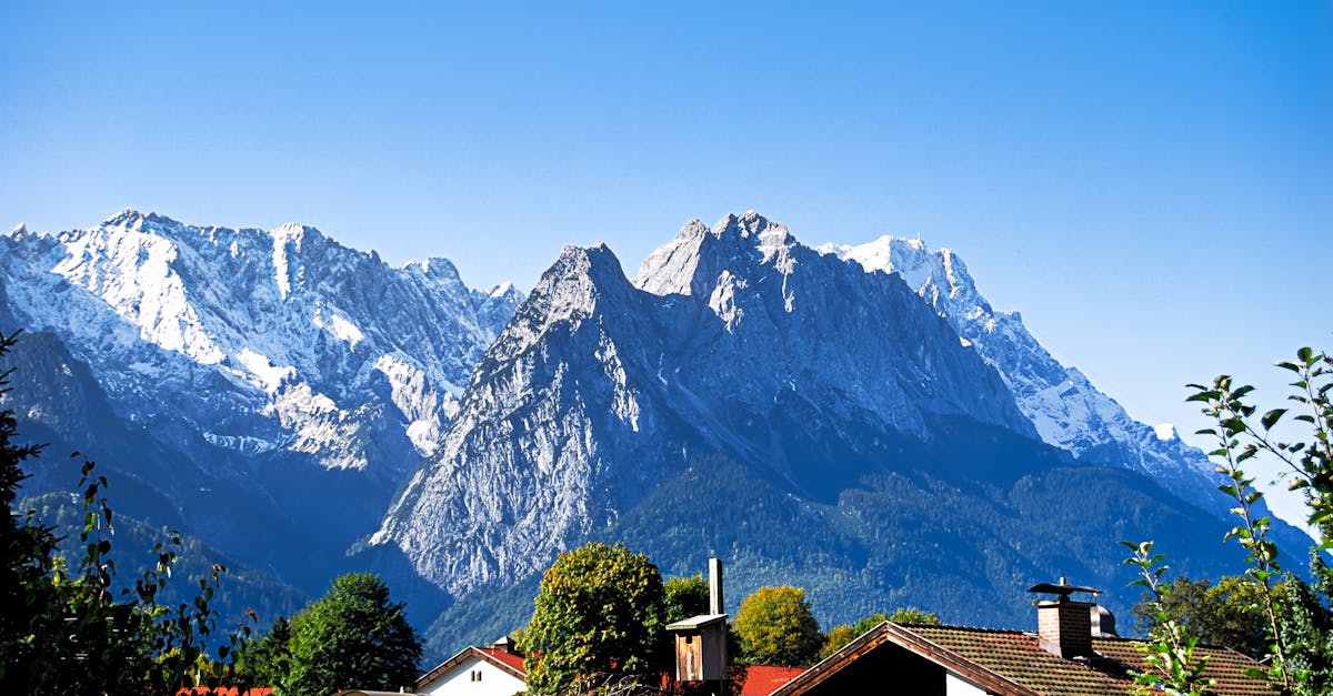 Sunny view of the Bavarian Alps in Garmisch-Partenkirchen with snow-capped peaks and houses.