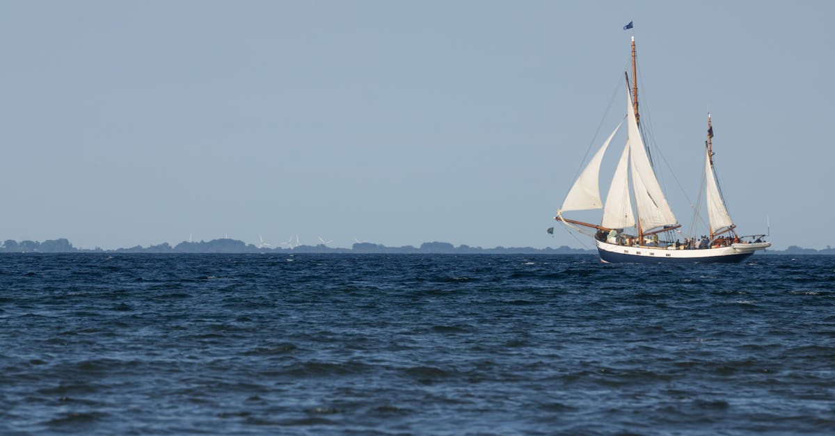 A sailing ship gracefully navigates the open sea under clear blue skies.