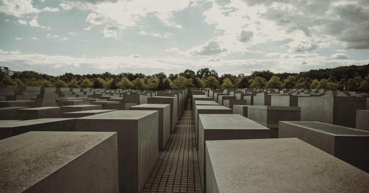 A view of the Holocaust Memorial in Berlin under a dramatic and cloudy sky.