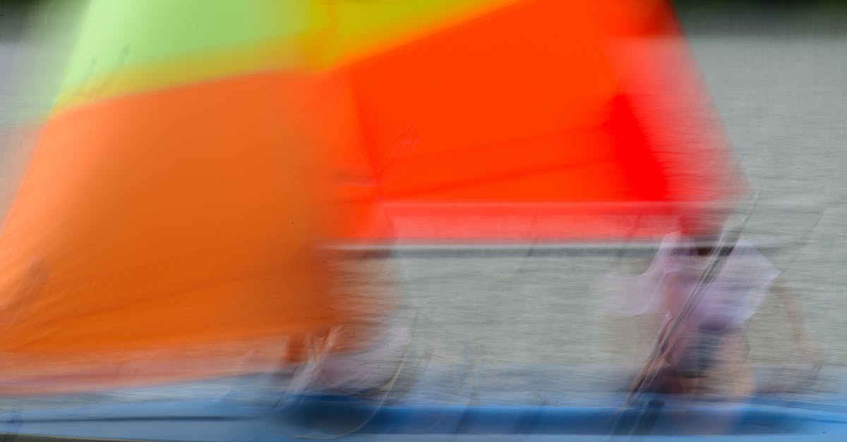 Artistic blur of a vibrant sailboat in motion on a serene lake, capturing dynamic colors and movement.
