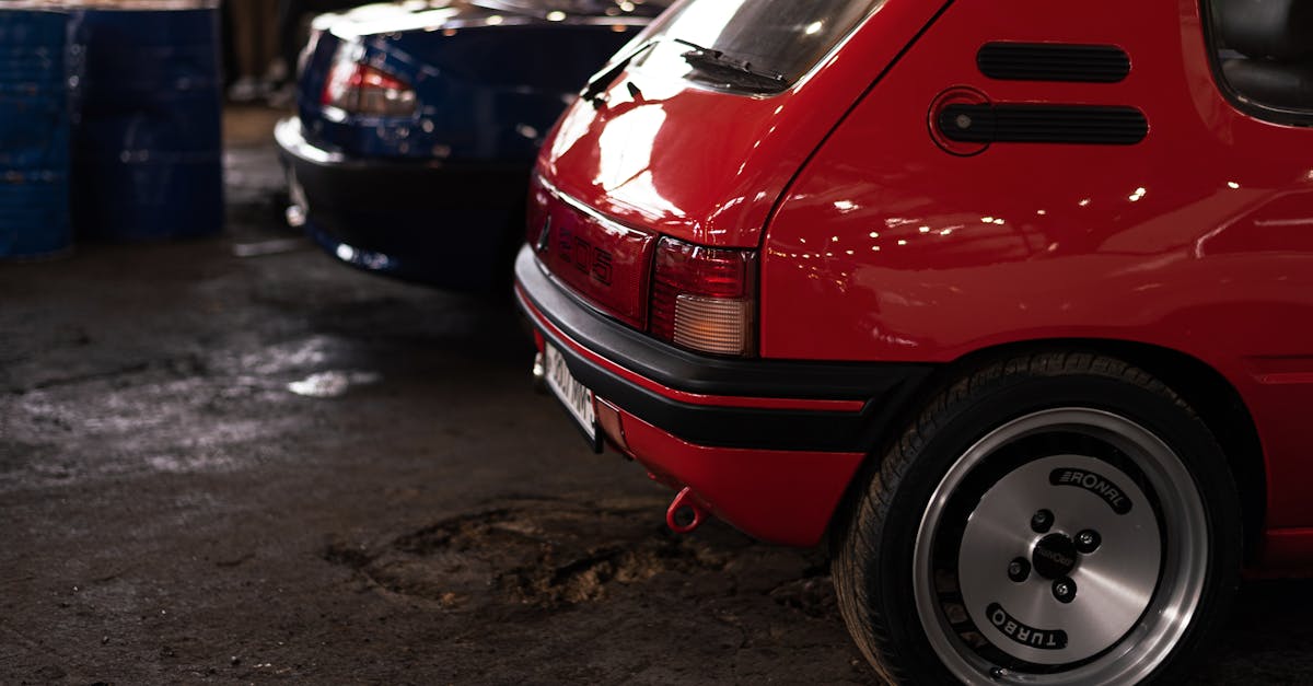 A vibrant red Peugeot 205 hatchback captured in a dimly lit urban environment.