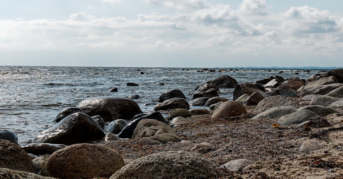 Serene rocky beach with cloudy sky and gentle waves on a tranquil day.