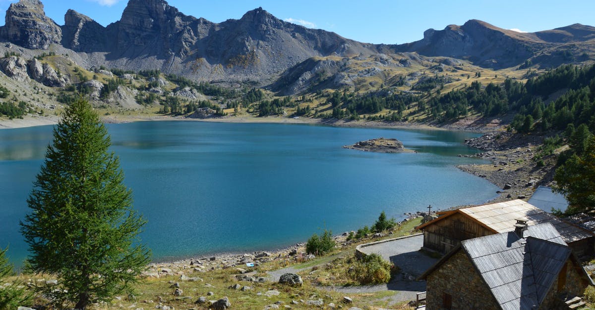 Stunning mountain lake with wooden cabins surrounded by rocky peaks and lush greenery.