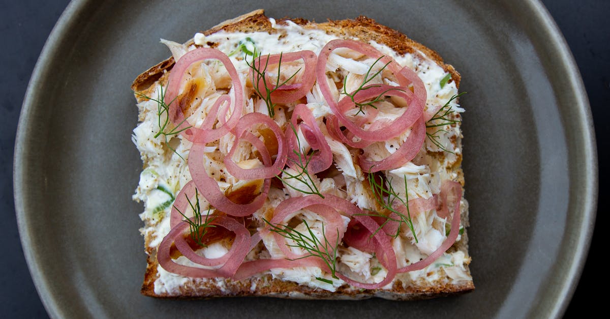 Open-faced sandwich topped with smoked whitefish, pickled onions, and dill.