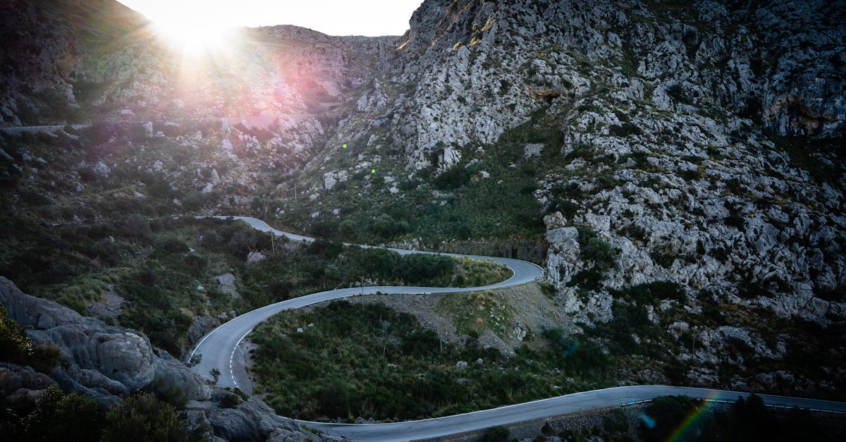 Winding mountain road with rocky landscape at sunrise, perfect for adventure seekers.