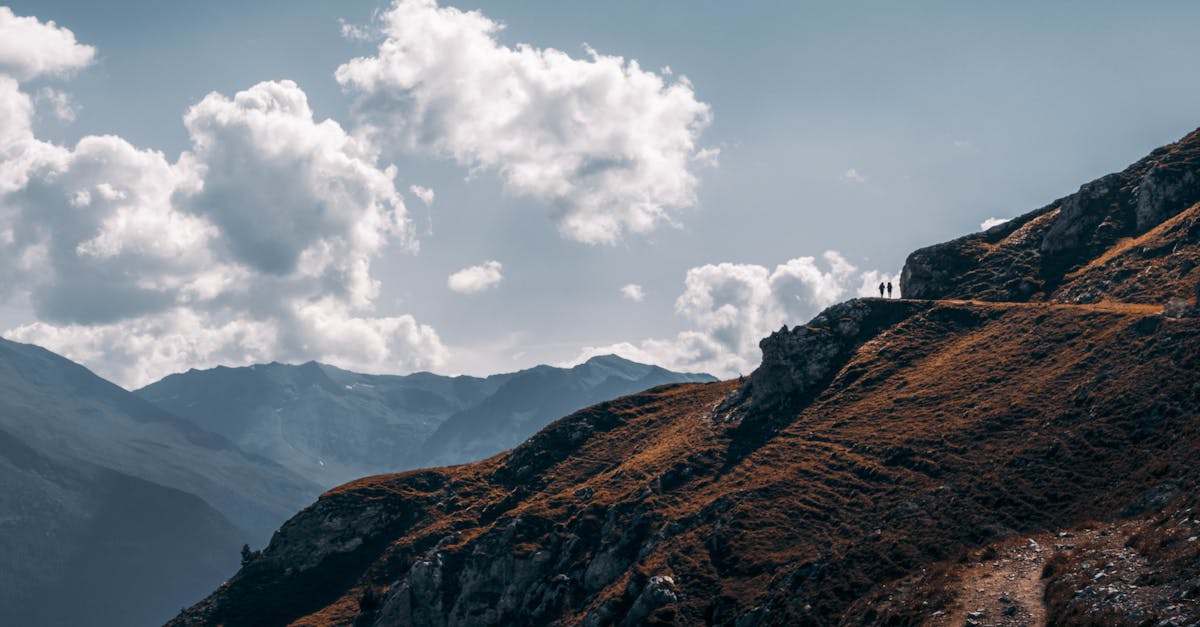 Two hikers enjoying a stunning mountain view under a cloudy sky at sunset.