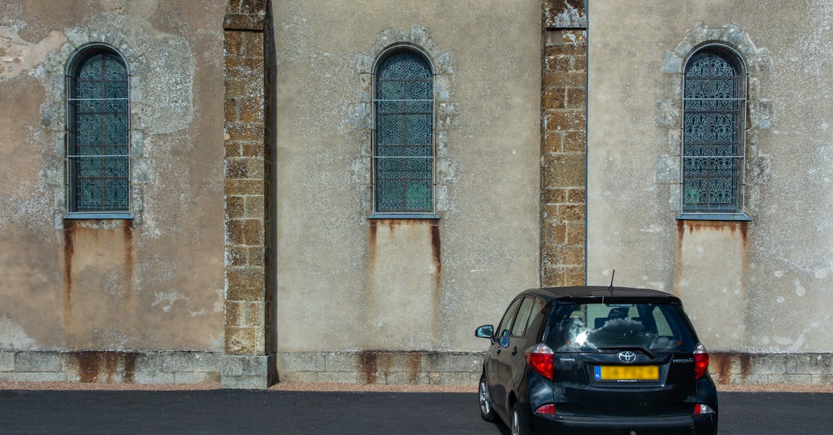 A black Toyota Verso parked in front of a historic stone building with arched windows, evoking an urban vintage feel.