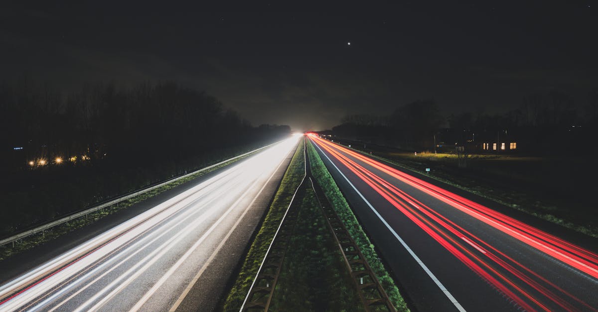 Long exposure shot of car light trails on a rural highway at night.