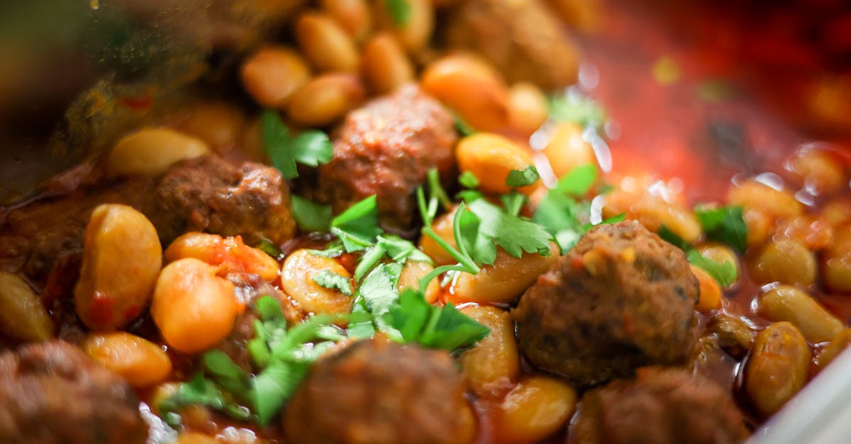 Close-up of a mouth-watering bean and meatball stew garnished with fresh herbs.