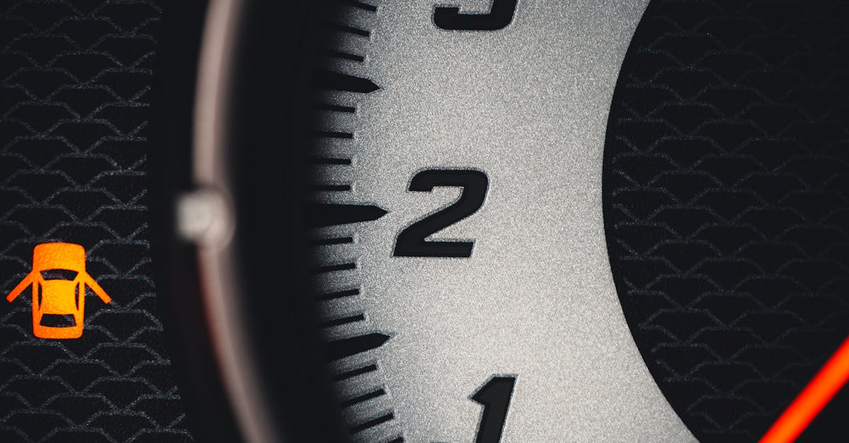 Detailed close-up of a car tachometer featuring a warning icon, focusing on the numbers with modern design elements.