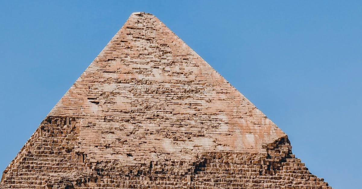 Close-up photo of the Great Pyramid's top under a clear blue sky, showcasing ancient architecture.