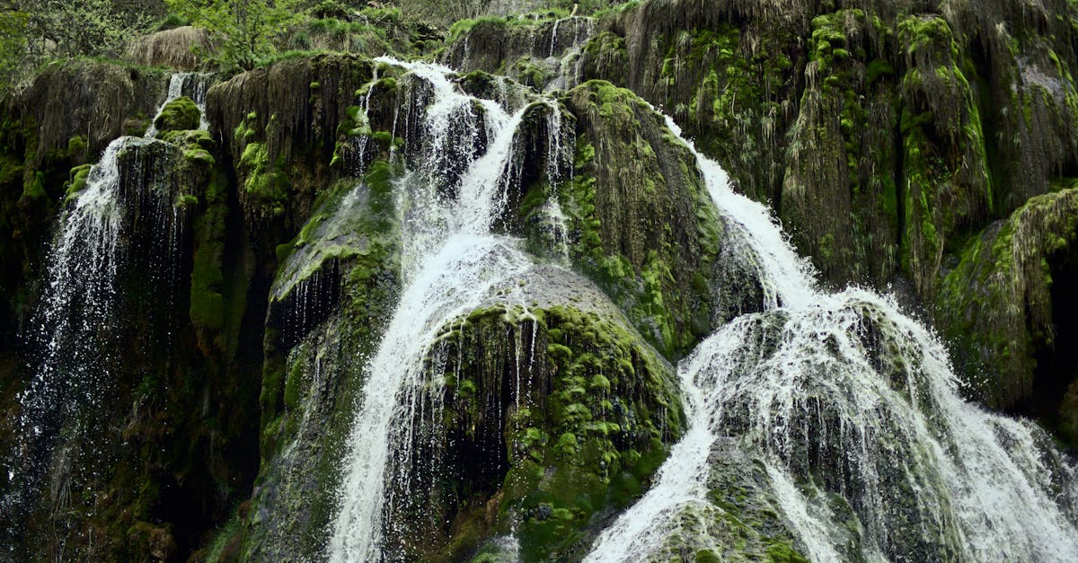 Stunning waterfall cascading down moss-covered rocks, France, captured in serene natural setting.