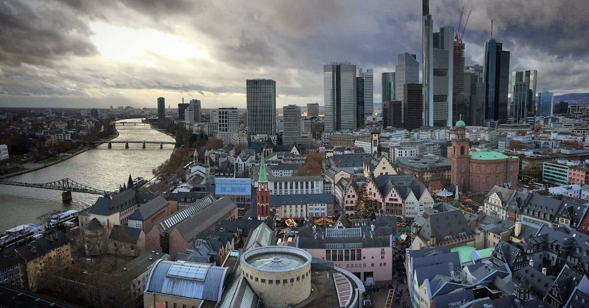 Aerial view of Frankfurt's modern skyline and historic center along the Main river at twilight.