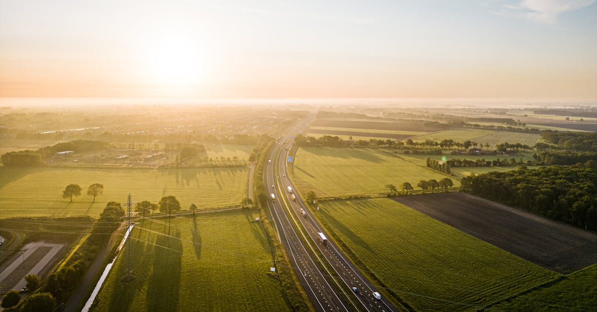Scenic aerial shot of Hoogeveen, Netherlands, showcasing vibrant fields and a winding road at sunset.