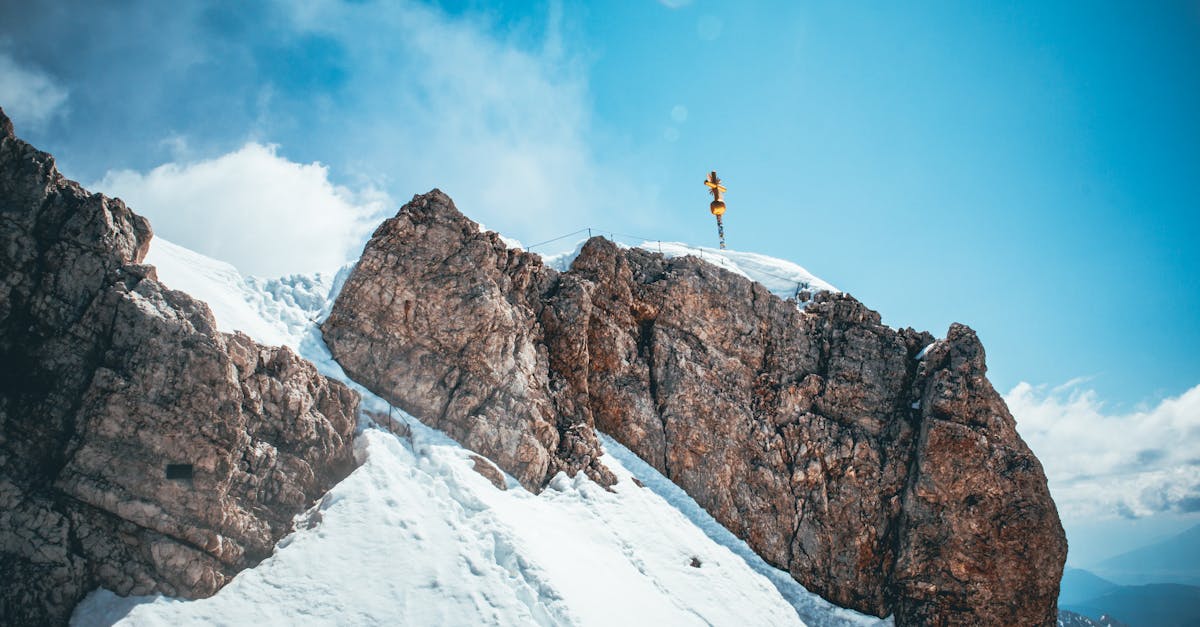Stunning view of the snowcapped Zugspitze peak with a prominent cross under a clear blue sky.