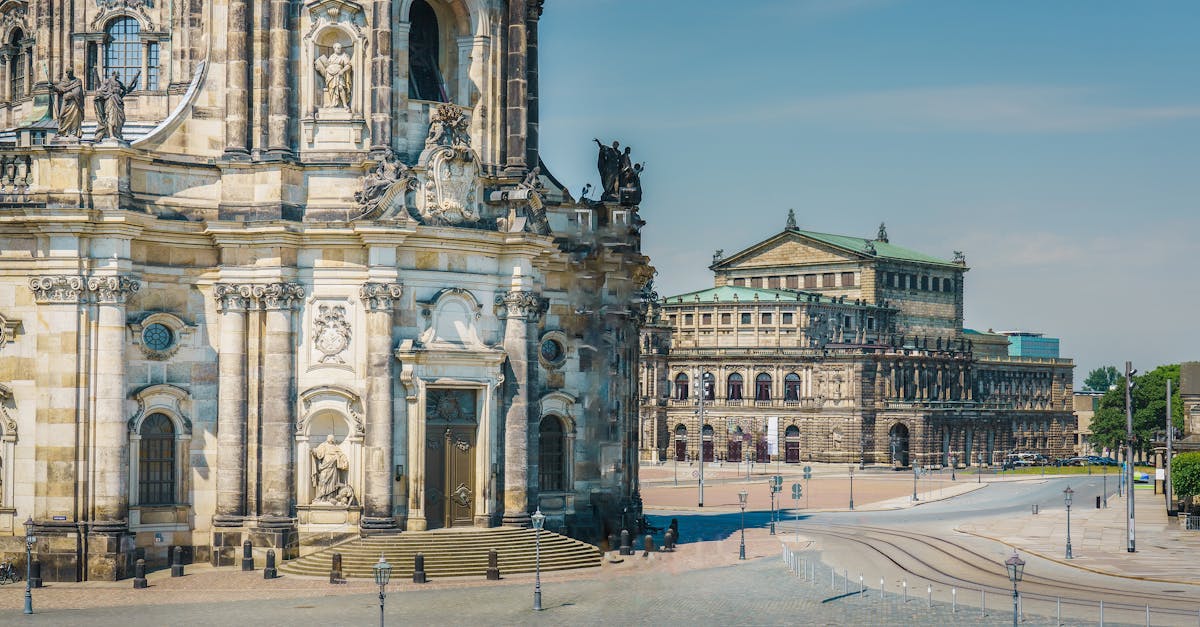View of Dresden's iconic Semperoper and Hofkirche buildings under a clear blue sky.