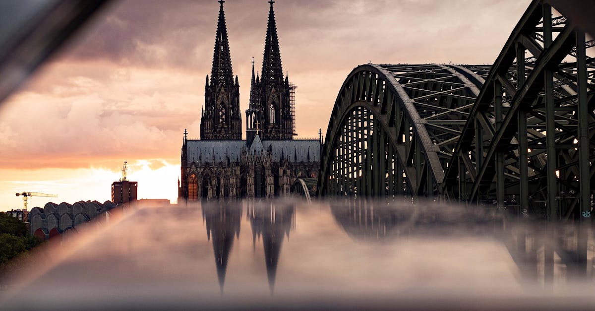 Majestic view of Cologne Cathedral and Hohenzollern Bridge at sunset, capturing gothic architecture.