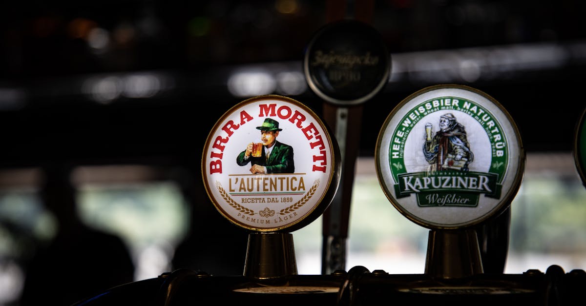 Close-up of beer taps featuring Birra Moretti and Kapuziner in a dimly lit bar.