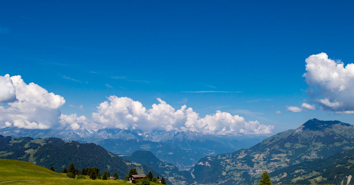 A serene mountain landscape under a vivid blue sky and fluffy clouds.