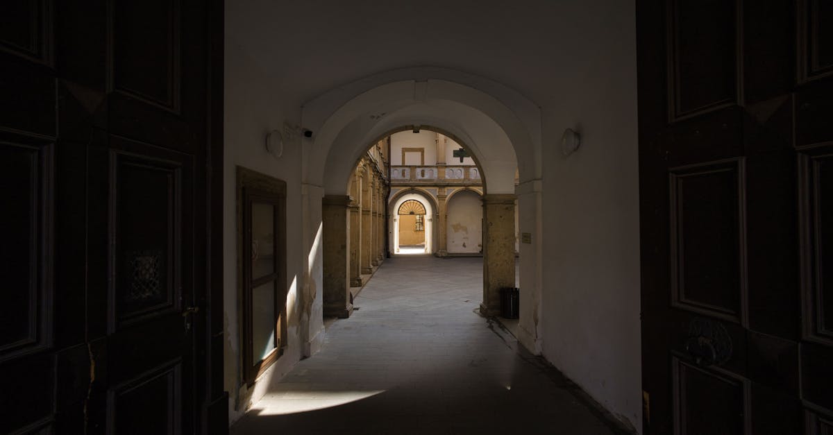 Explore the serene beauty of a historic courtyard corridor in Jičín, Česko, captured in dramatic light and shadow.