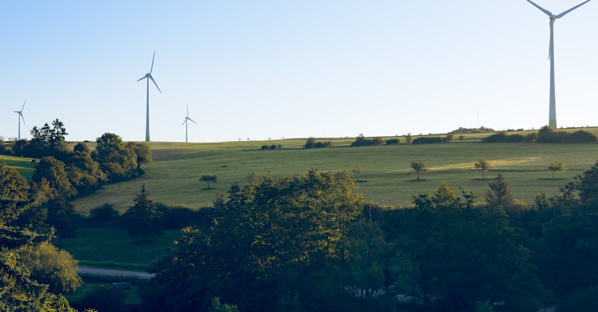 Scenic view of wind turbines on grassy hills in Luxembourg under clear blue sky.