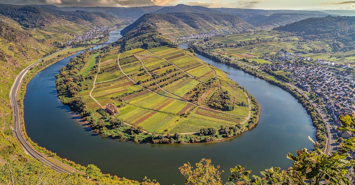 Scenic aerial shot of Moselle River's winding path through Bremm, Germany, showcasing lush vineyards.