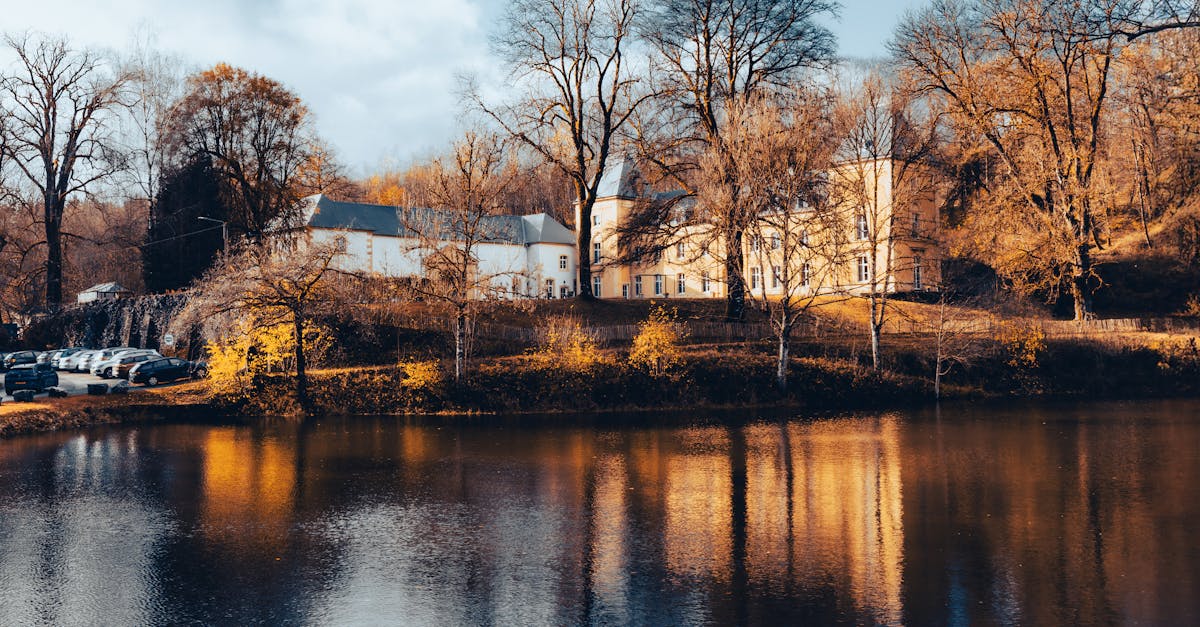 Scenic autumn view of a town with colorful trees reflected in a serene lake.