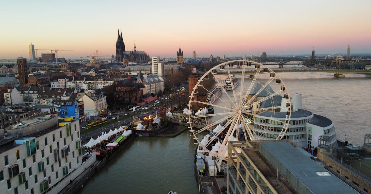 A scenic view of Cologne's Ferris Wheel and the city skyline at dusk with the Rhine River.