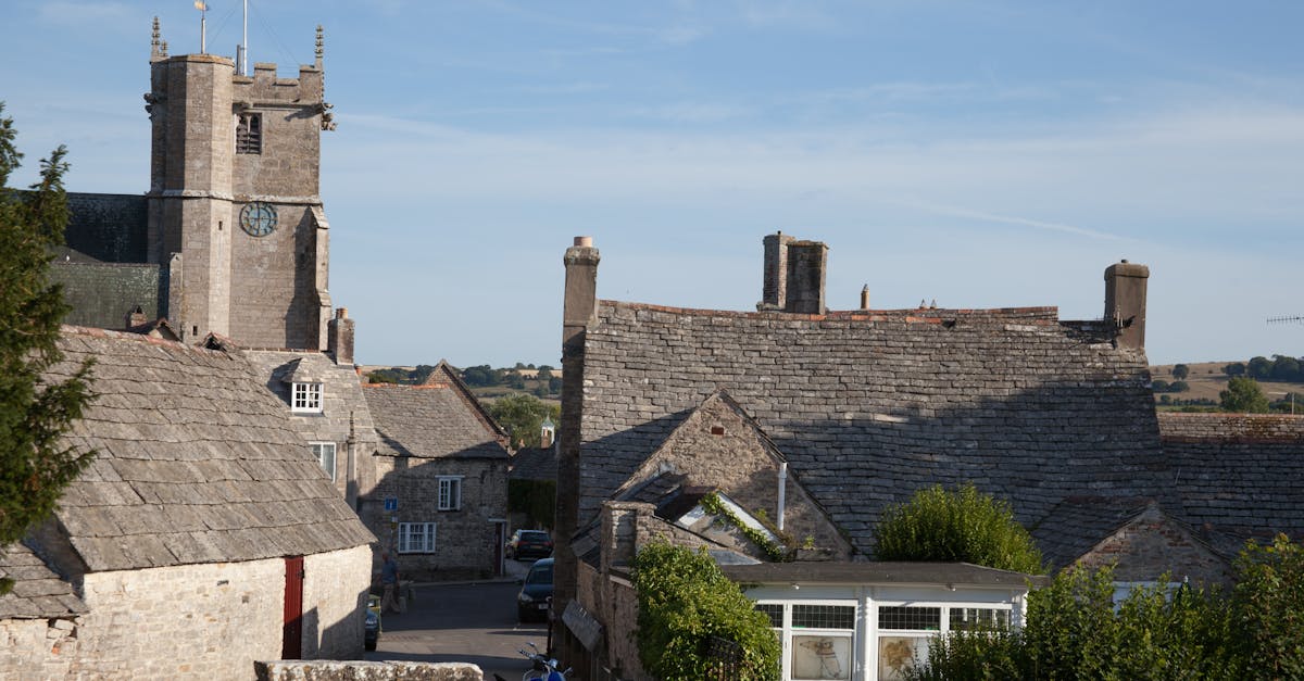 Charming view of historic rooftops and tower in Corfe Castle village, England.