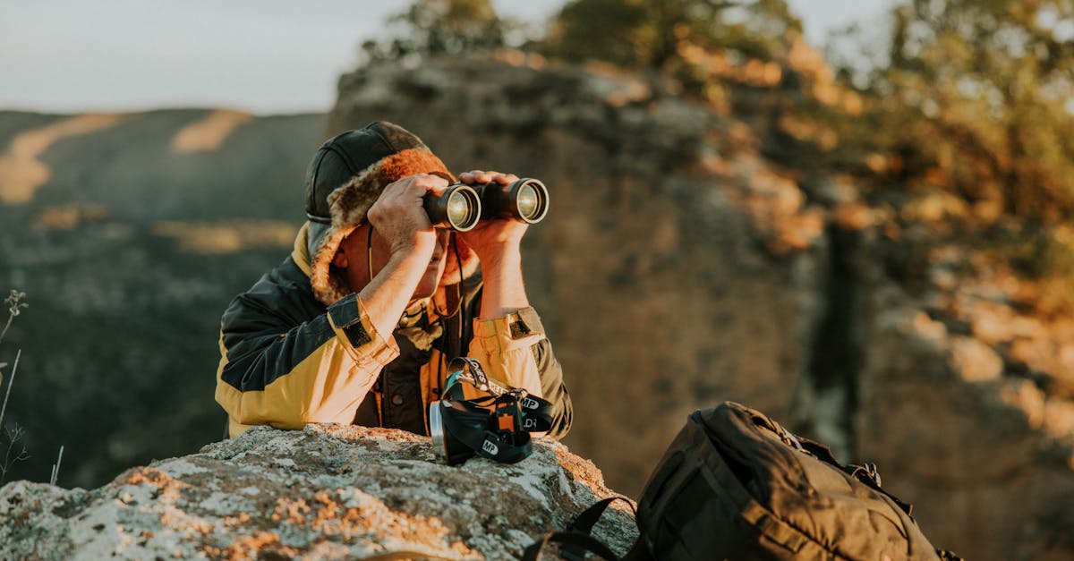 An adventurer observes through binoculars in a picturesque canyon landscape during dusk.