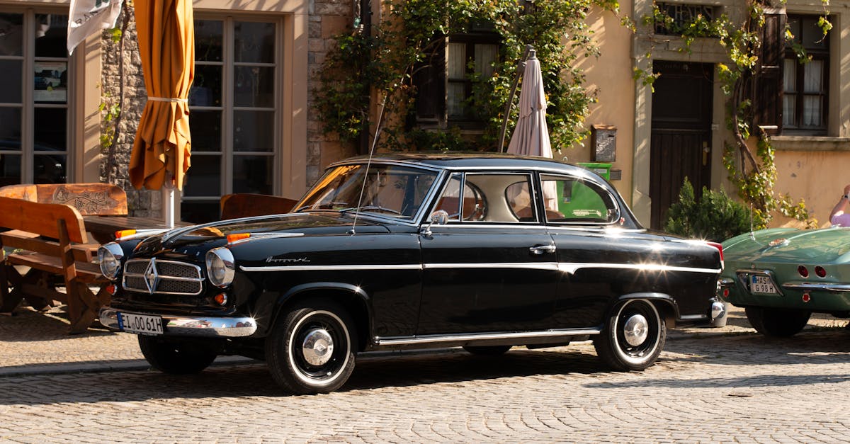 Black Borgward Isabella parked on a cobblestone street in a sunny city, highlighting its classic charm.