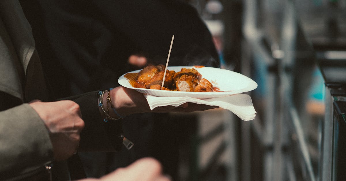 Person holding a plate of savory street food at an outdoor market.