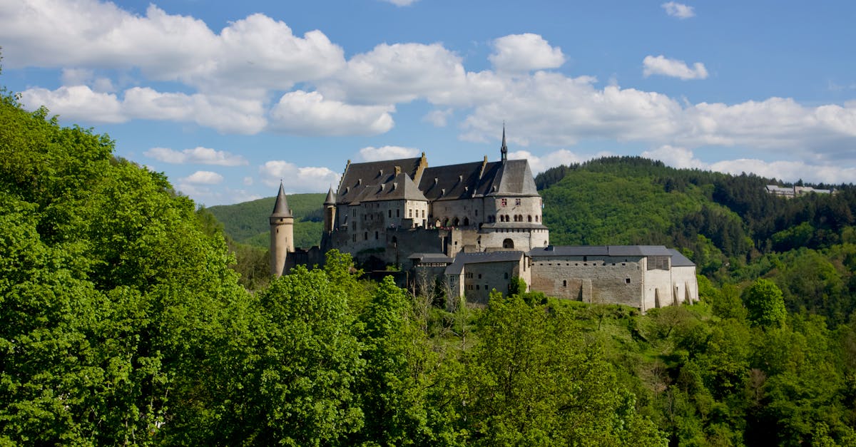 A stunning aerial view of Vianden Castle surrounded by lush forests in Luxembourg.