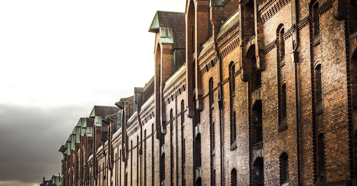 Dramatic view of historic brick warehouses with green gabled roofs at sunrise.