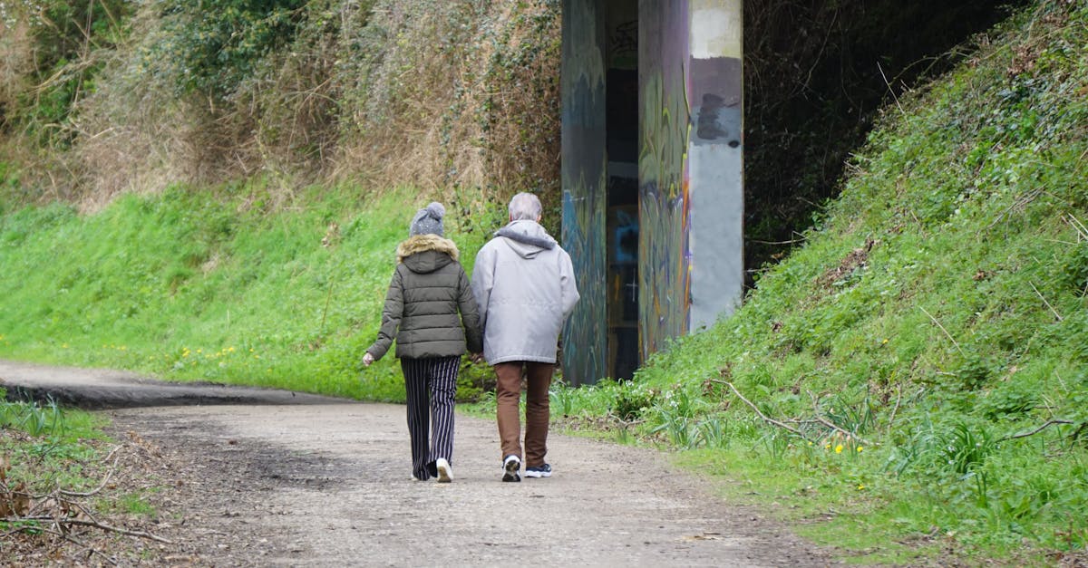 A couple enjoys a leisurely walk on a lush countryside path surrounded by greenery.