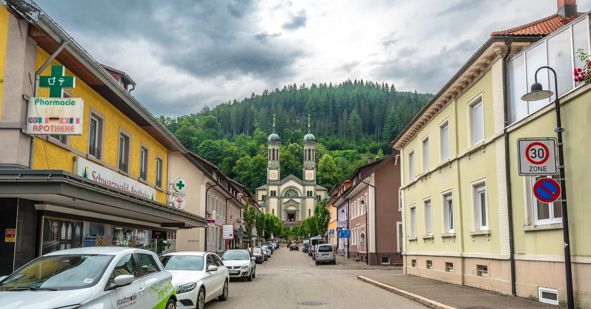 Picturesque street view in Germany featuring a church, lush forest, and traditional buildings.