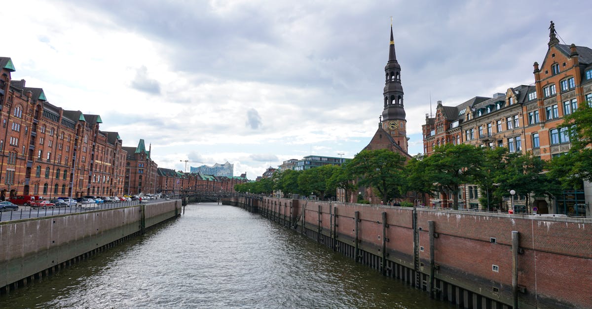 Explore the picturesque canal in Hamburg with historic brick architecture under a cloudy sky.