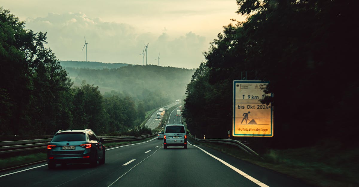 A calm drive along a misty highway with visible wind turbines and forest surroundings.