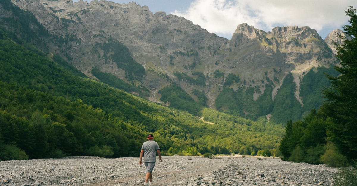 Person hiking in Valbonë Valley, Albania with stunning mountain backdrop.