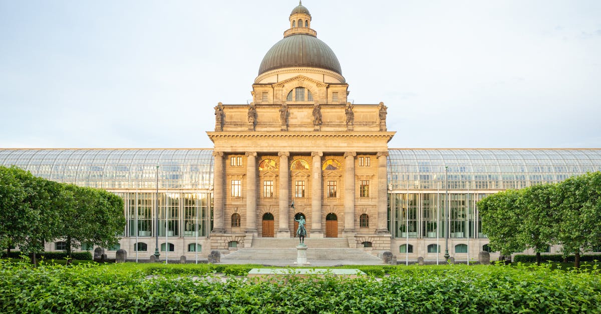 Front view of the Bavarian State Chancellery in Munich with lush gardens in the foreground.
