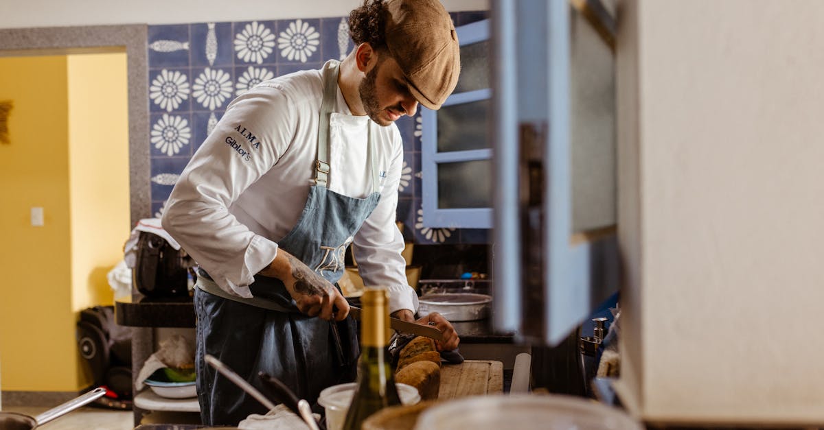 Chef wearing uniform and cap slicing bread in a contemporary kitchen setting.
